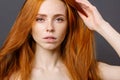 Redhead woman holding her healthy and shiny hair, studio grey Royalty Free Stock Photo