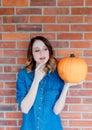 Redhead woman in jeans clothes holding orange autumn pumpkin Royalty Free Stock Photo