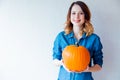 Redhead woman in jeans clothes holding orange autumn pumpkin Royalty Free Stock Photo