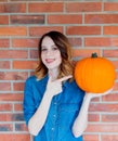 Redhead woman in jeans clothes holding orange autumn pumpkin Royalty Free Stock Photo