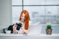 Redhead woman looking at camera while working on laptop Royalty Free Stock Photo