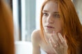 Redhead woman looking at her reflection in mirror