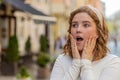 Redhead woman looking surprised at camera shocked by sudden win good victory news wow in city street Royalty Free Stock Photo