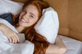 Redhead woman lying in the bed with smartphone Royalty Free Stock Photo