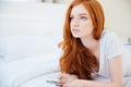 Redhead woman lying on the bed with smartphone Royalty Free Stock Photo