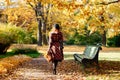 Redhead woman in plaid coat and beret walks through the park at sunny day, back view. fall season Royalty Free Stock Photo