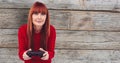 Redhead woman playing video game against wall