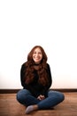 redhead woman sitting on the floor smiling at the camera Royalty Free Stock Photo