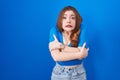 Redhead woman standing over blue background shaking and freezing for winter cold with sad and shock expression on face Royalty Free Stock Photo