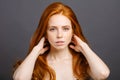 Redhead woman holding her healthy and shiny hair, studio grey Royalty Free Stock Photo