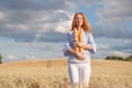 Redhead woman with two french loaves in ripe wheat field