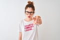 Redhead woman wearing funny t-shirt with irony comments over isolated white background pointing with finger to the camera and to