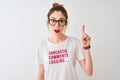 Redhead woman wearing funny t-shirt with irony comments over isolated white background surprised with an idea or question pointing