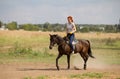 A redhead woman in yellow gloves riding a horse in nature