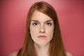 Redhead young serious woman looking at camera over pink background.