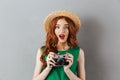 Redhead young shocked lady photographer holding camera.