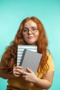 Redhead young woman holding blank books looking at the camera isolated on blue Royalty Free Stock Photo
