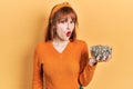 Redhead young woman holding sunflower seeds bowl scared and amazed with open mouth for surprise, disbelief face Royalty Free Stock Photo