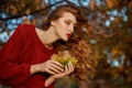 Redhead young woman in a red sweater walks in the park. Autumn beauty portrait of a fashionable Red-haired woman at sunset