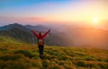 Redheaded girl athlete with a backpack and sticks stands on the green hillocks. Royalty Free Stock Photo