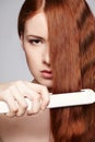 Redheaded woman with hair straightening irons Royalty Free Stock Photo