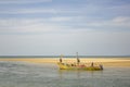 Indian fishermen in a big yellow sea boat on a background of yellow sand and blue ocean Royalty Free Stock Photo