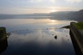 Redmires reservoir dam inlet overflow reflecting a misty water sunset Royalty Free Stock Photo