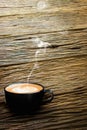 Redolent cappuccino coffee with smoke on old wooden floor. Royalty Free Stock Photo