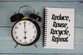 Reduce, Reuse, Recycle, Repeat text written on notepad with alarm clock on wooden background Royalty Free Stock Photo