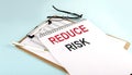 REDUCE RISK text on notepad on clipboard with chart on blue background, concept closeup. Business and finance concept Royalty Free Stock Photo