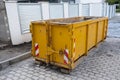 Reduced size of small and narrow yellow metal dumpsters container, construction trash, street reconstruction