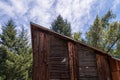 A redwood sided house has a peeked roof