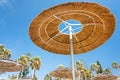 Reed beach umbrellas, sunshades against blue sky on the beach. Bamboo parasols, straw umbrellas on on white sandy Royalty Free Stock Photo