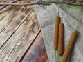 Reeds, cattail with sack fabric on wooden background.