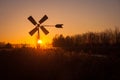 Dutch pumping windmill is silhouetted against the evening sky.