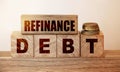 Refinance Debt text on a wooden blocks and cubes and stack of coins. Overdue debts redeem and refinancing financial banking