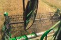 The reel and mirror of a combine harvester seen from farmer's perspective. Rapeseed harvesting season. The evolution
