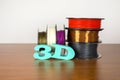 3D printing filament reels with text `3d` on wooden background