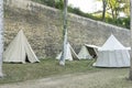 Reenactment of a medieval scene against the historical backdrop of an old city wall, village with tents of various designs with