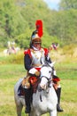 Reenactor-cuirassier dressed as Napoleonic war soldier rides a horse.