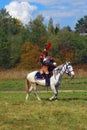 Reenactor cuirassier rides a white horse. Autumn trees background.
