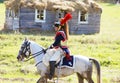 Reenactor dressed as Napoleonic war soldier rides a horse.