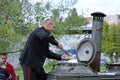 Reenactor dressed in uniform of USSR navy sailor puts food in the plate from the field mobile kitchen