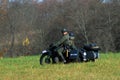 A reenactor rides a retro motorbike.