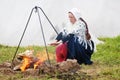 Reenactor woman warming his hands by the fire