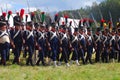 Reenactors dressed as Napoleonic war soldiers march holding guns