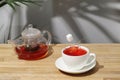 Ref fruit tea on wooden table. sugar cube falling in cup. splash of tea. tea pot with fruit tea Royalty Free Stock Photo
