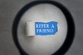 Refer A Friend text on torn paper with magnifying glass. Network concept. Royalty Free Stock Photo