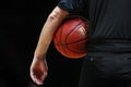 A referee with black uniform holds the official basket game ball Royalty Free Stock Photo