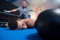 Referee gesturing with arms outstretched by unconscious male boxer Royalty Free Stock Photo